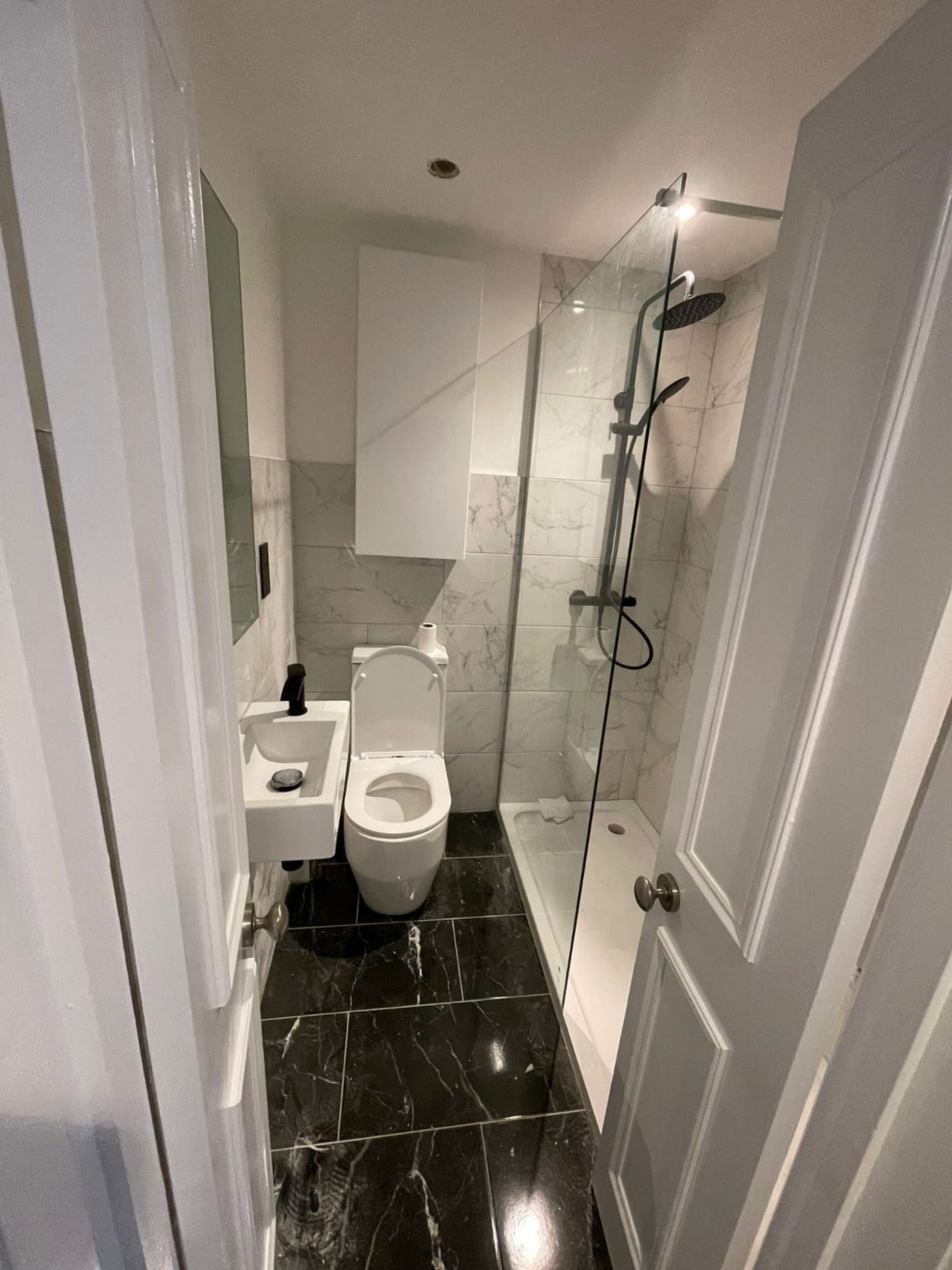 A modern bathroom with a toilet, sink, and glass-enclosed shower.