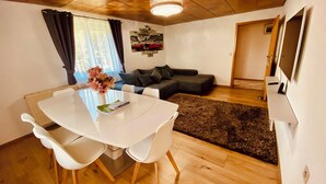 A modern living room with a white dining table, white chairs, a black sofa, and a brown rug. - 87452 Altusried district Frauenzell, near Center Parcs Leutkirch im Allgäu (Altusried)