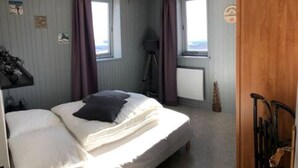 A bedroom with a bed, two windows, a tripod, and a wooden door. - 7 Couchages + Bébé, sur les Pistes + Parking (Besse-et-Saint-Anastaise)