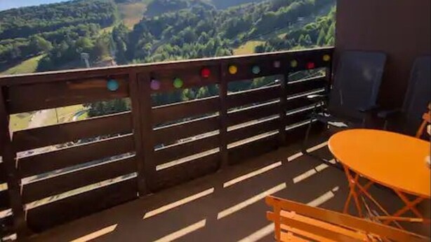 A balcony with a wooden railing, a table, and chairs. - 7 Couchages + Bébé, sur les Pistes + Parking (Besse-et-Saint-Anastaise)