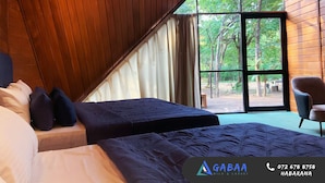Ein Schlafzimmer mit zwei Betten, einem großen Fenster und Blick ins Freie.