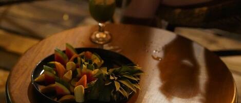 Una mesa de comedor con una ensalada de frutas y un cóctel encima.