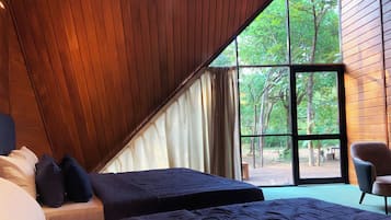 A bedroom with two beds, a large window, and a view of the outdoors.