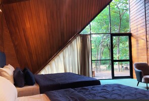 A bedroom with two beds, a large window, and a view of the outdoors.