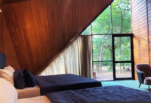 A bedroom with two beds, a large window, and a view of the outdoors.
