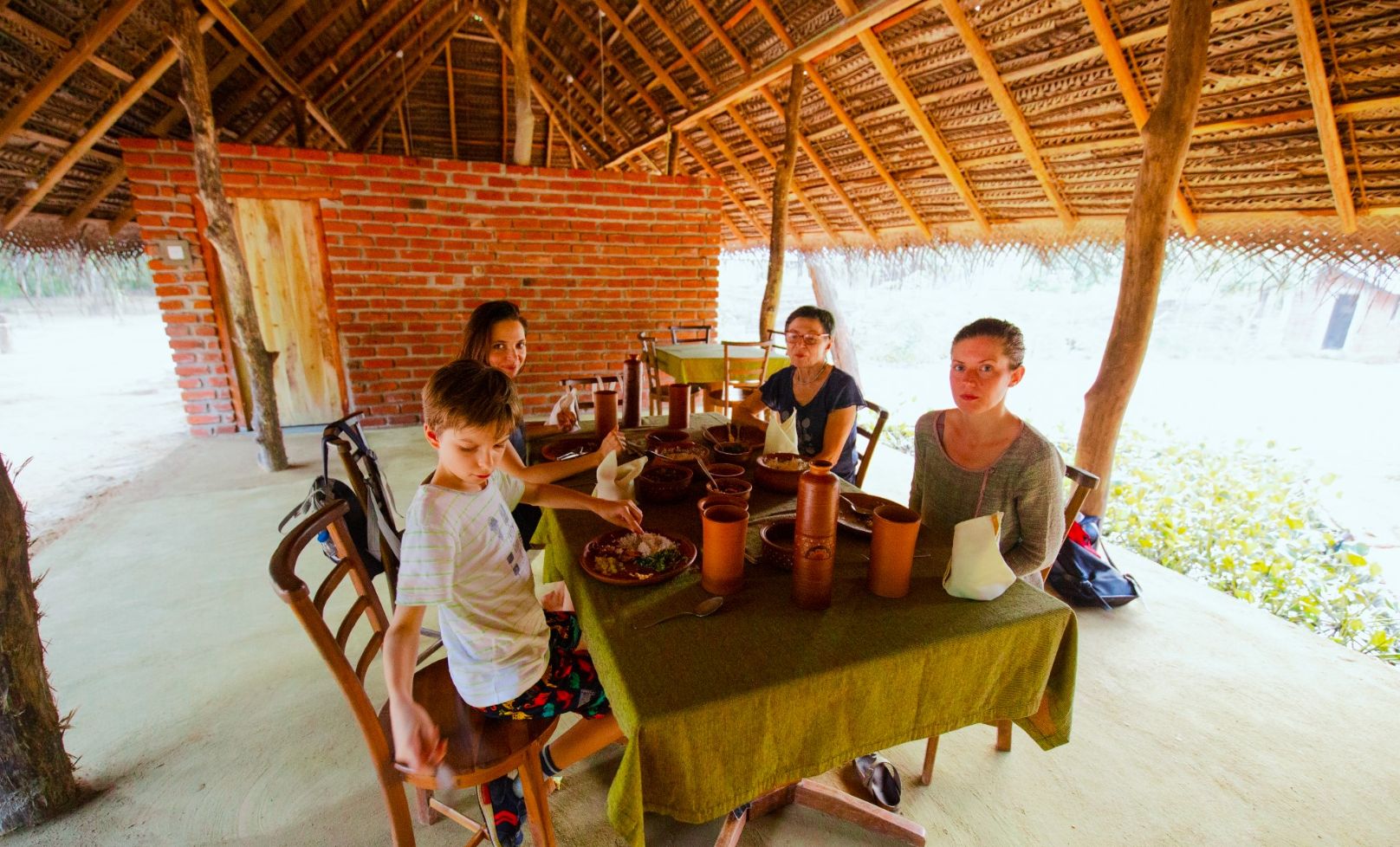 Un comedor rústico con pared de ladrillo, techo de madera y una mesa lista para una comida.