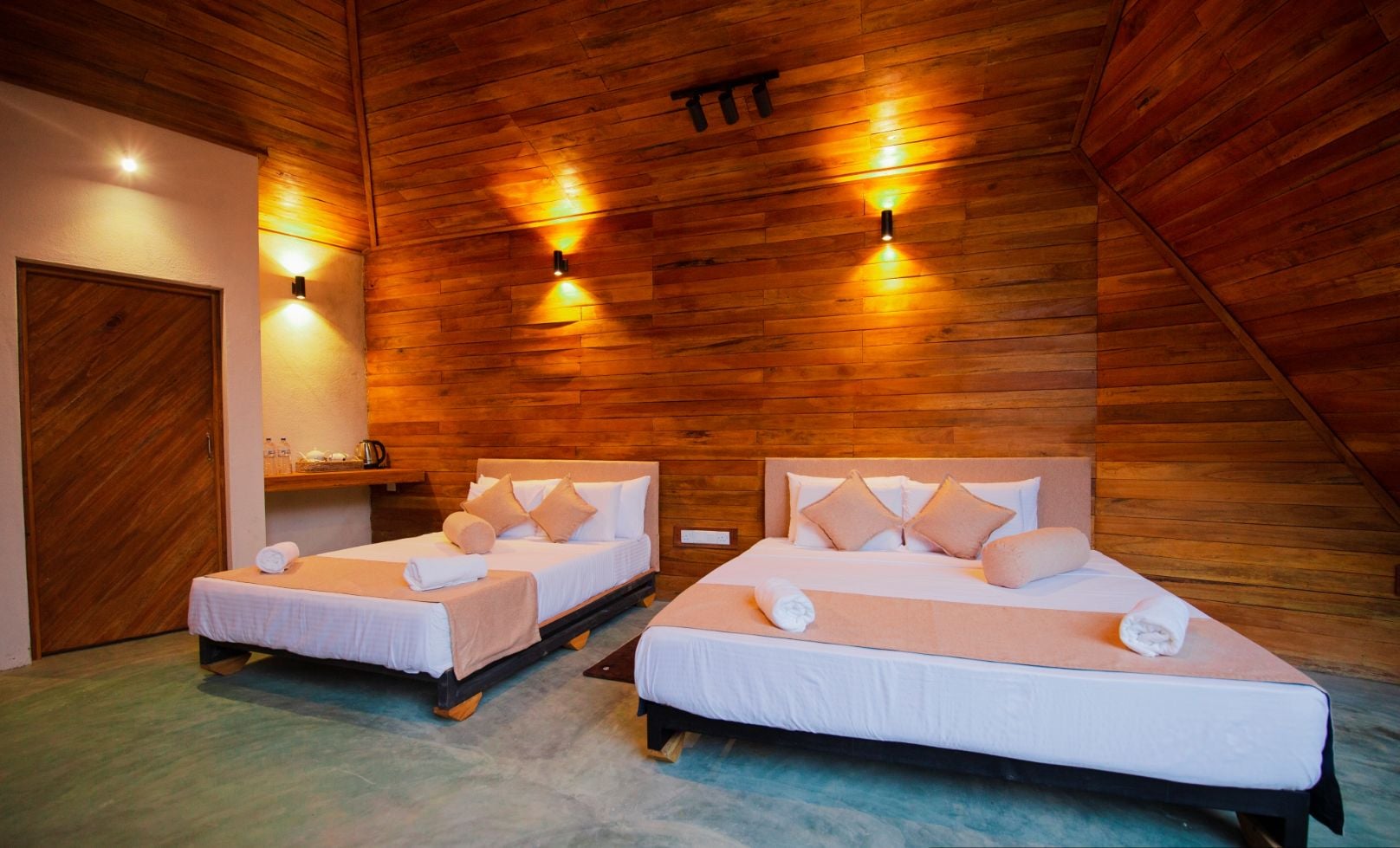 Deux lits simples avec des têtes de lit en bois et une literie beige, dans une pièce aux murs et au plafond en bois.
