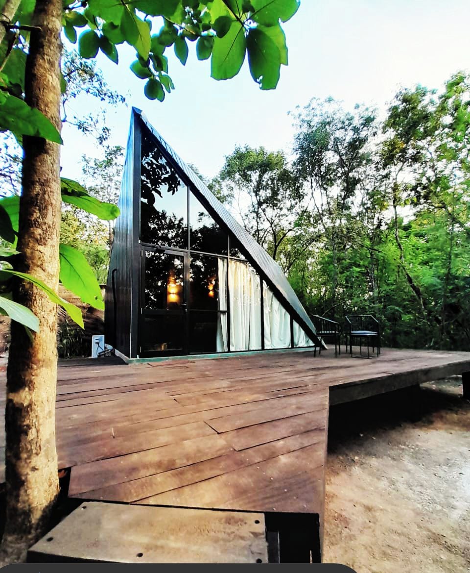 A modern building with a sloped roof and large windows, surrounded by trees.