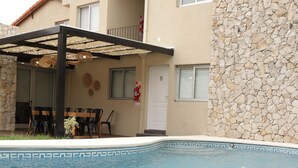 A swimming pool with a stone wall and a covered patio area. - ROZAS (Ezeiza)