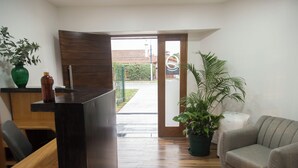 A modern interior with a wooden reception desk, a grey sofa, and a potted plant. - ROZAS (Ezeiza)