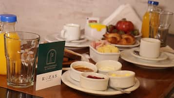 A breakfast setting with various dishes, including toast, fruit, and beverages, on a wooden table.