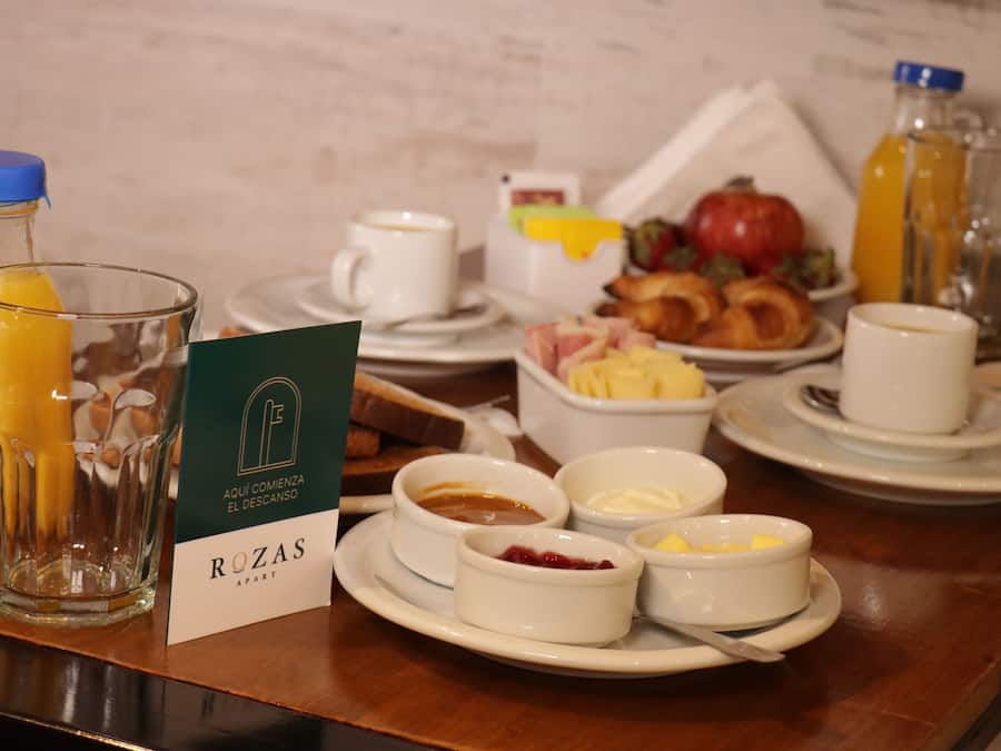 A breakfast setting with various dishes, including toast, fruit, and beverages, on a wooden table.