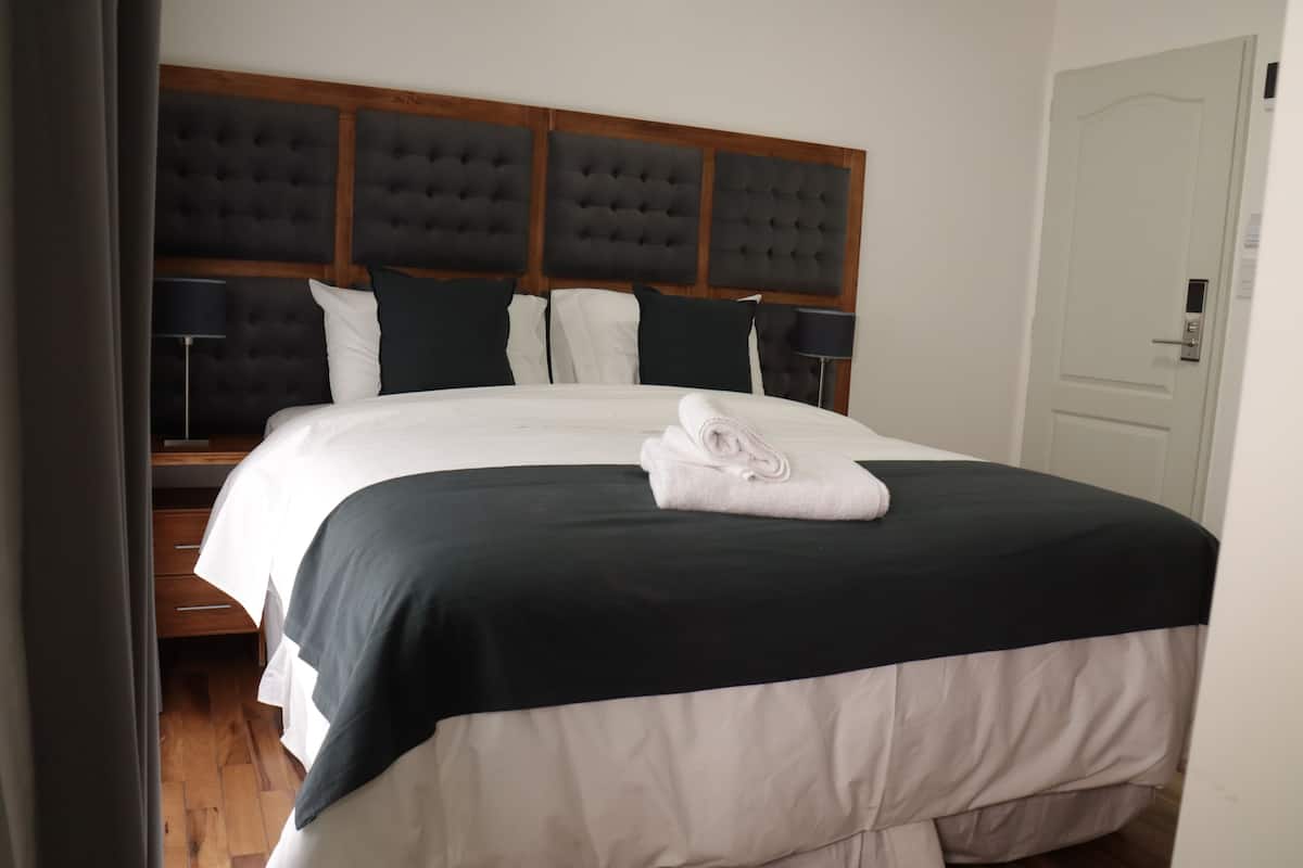 A neatly made bed with a black and white duvet, a wooden headboard, and two bedside lamps.