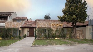 A residential property named 'ROZAS' with a stone facade, tiled roof, and a well-maintained lawn. - ROZAS (Ezeiza)
