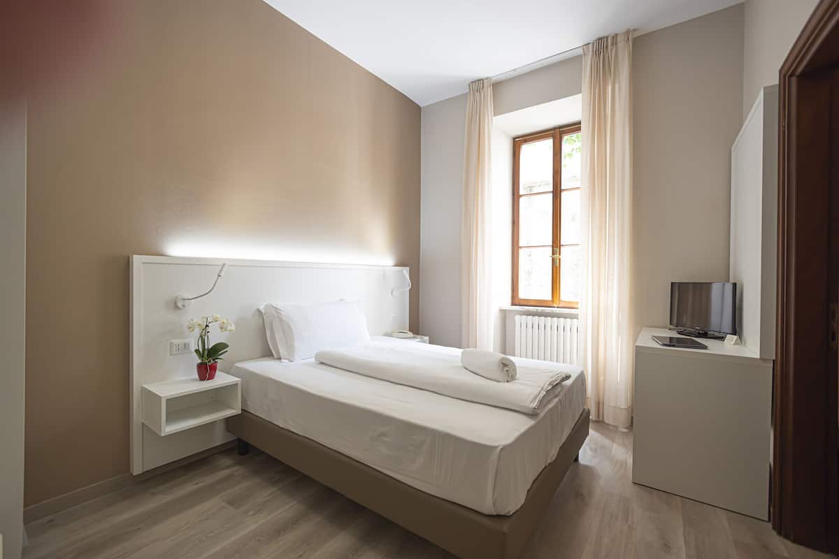 Une chambre moderne avec un lit, une table de chevet, une télévision et une fenêtre avec des rideaux.