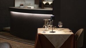 A restaurant with a bar area, tables set with glasses and cutlery, and a modern geometric light fixture. - LVG Hotel Collection - Il Portico (Cannobio)