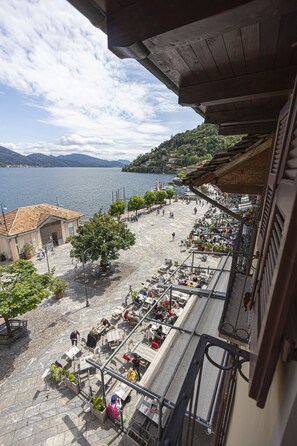 Une terrasse avec des sièges extérieurs donnant sur un lac, entourée d’immeubles et d’arbres.