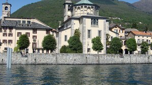 A historic building with a bell tower, a dome, and a stone wall along a waterfront. - LVG Hotel Collection - Il Portico (Cannobio)