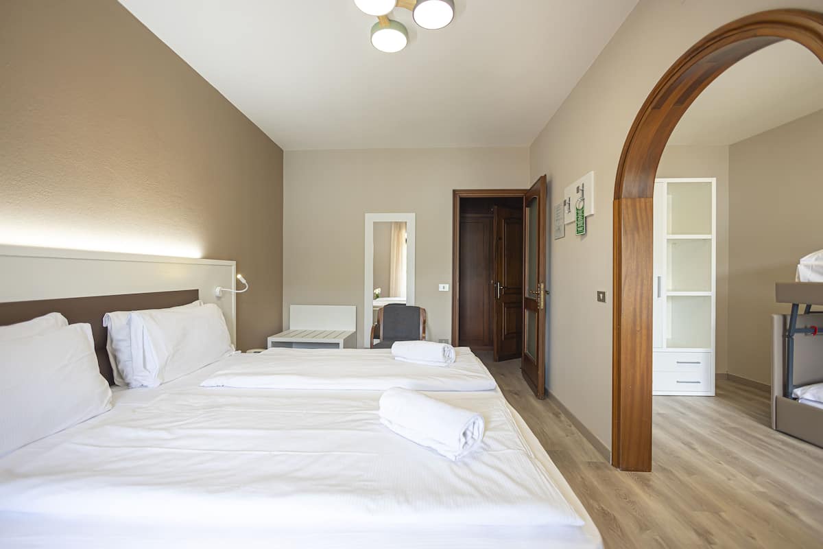 Une chambre d’hôtel avec deux lits, une arche en bois, un bureau et une armoire.