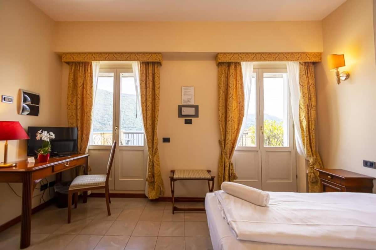Une chambre d’hôtel équipée d’un lit, d’un bureau, d’une chaise, d’une télévision et d’une petite table.
