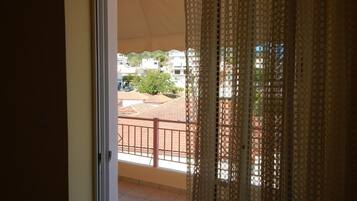 A balcony with a view of a residential area, featuring a tiled floor and a metal railing.