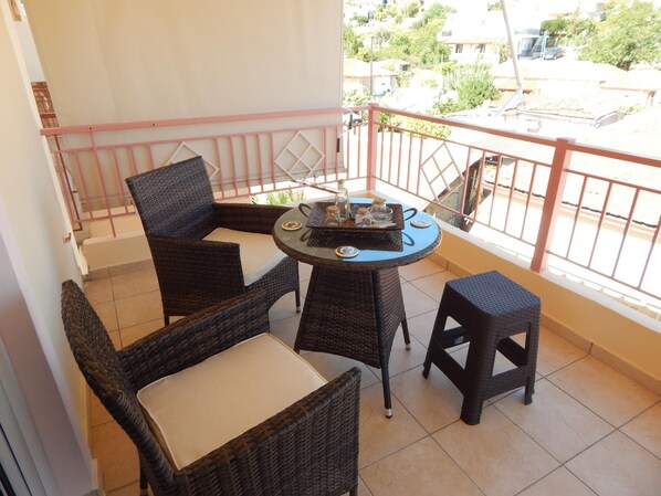 A balcony with wicker furniture, a small table, and a view of the neighborhood. - Angela s Apartment With Beautiful Balcony View (Kamena Vourla)