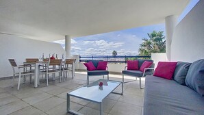 Eine Terrasse mit Esstisch, Stühlen, einer Couch und einem Couchtisch.