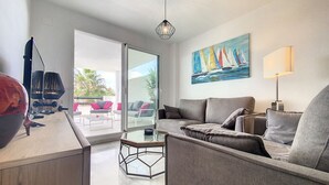 Ein modernes Wohnzimmer mit einer Couch, einem Couchtisch und einem Gemälde mit Segelbooten.