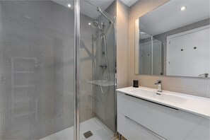 A modern bathroom with a glass-enclosed shower, a white sink, and a large mirror. - Via Celere 2405 Beautiful apartment with seaview (Casares)