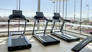 A gym with treadmills and a bench, large windows, and a view of a bridge. - Via Celere 2405 Beautiful apartment with seaview (Casares)