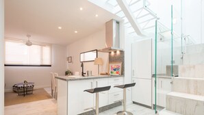 A modern kitchen with white cabinets, a granite countertop, and two bar stools. - Estropada 1, detached apartment in Pedregalejo, Malaga, with sea views (Málaga)