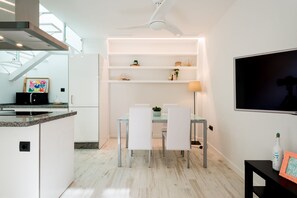 A modern kitchen with a dining area, white cabinetry, a ceiling fan, and a TV on the wall. - Estropada 1, detached apartment in Pedregalejo, Malaga, with sea views (Málaga)
