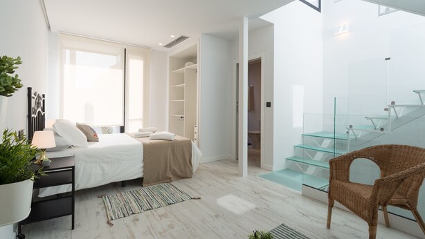 A modern bedroom with a bed, bedside table, and a glass staircase. - Estropada 1, detached apartment in Pedregalejo, Malaga, with sea views (Málaga)