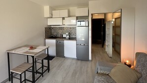 Une cuisine compacte comprenant un coin repas, un réfrigérateur, un four à micro-ondes et une machine à café.
