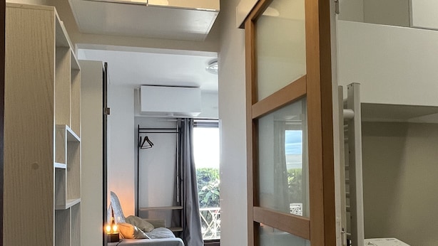 Une chambre d’hôtel moderne, équipée d’un lit, d’une armoire et d’un balcon.