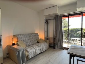 Uma sala de estar moderna com sofá, mesa e uma grande janela com vista para o verde.