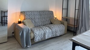 Une pièce moderne et minimaliste, avec un canapé gris à motifs, une petite table et une armoire intégrée.