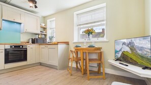 A modern kitchen with a dining area, a TV, and a window with a view.