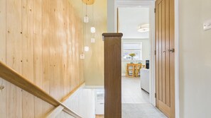 Un escalier en bois mène à une pièce où l’on aperçoit un coin cuisine au fond.