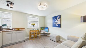 Un espacio habitable compacto con kitchenette, comedor y zona de estar con televisor.
