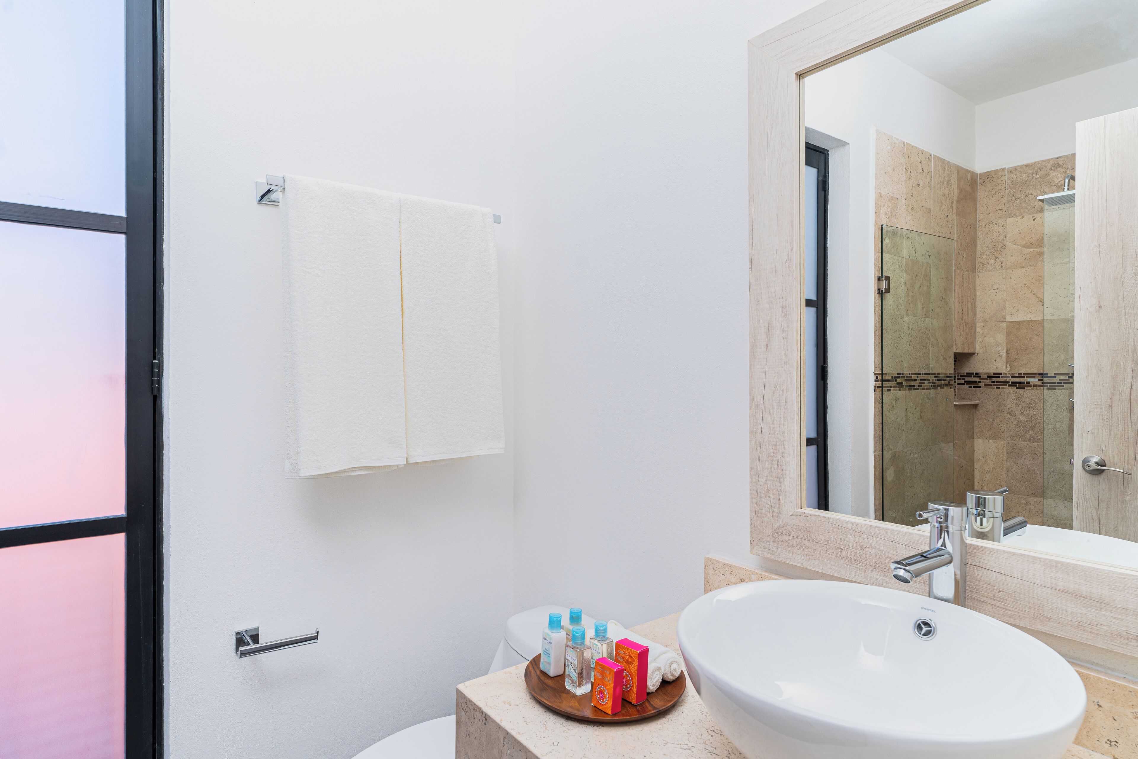 A modern bathroom with a large sink, a mirror, and a shower area.