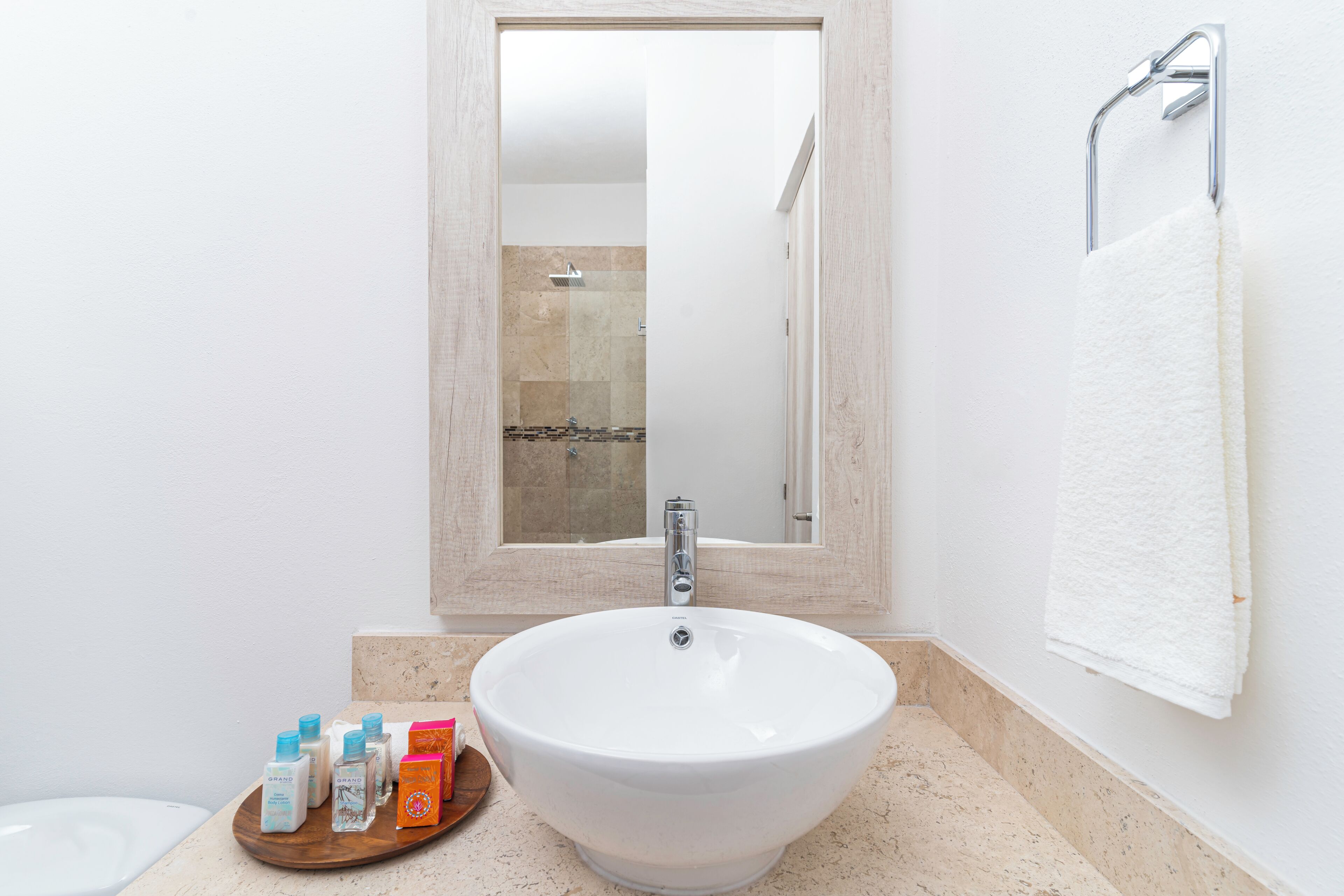 A bathroom with a large white sink, a mirror above it, and a towel hanging on the wall.