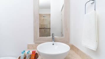 A bathroom with a large white sink, a mirror above it, and a towel hanging on the wall.