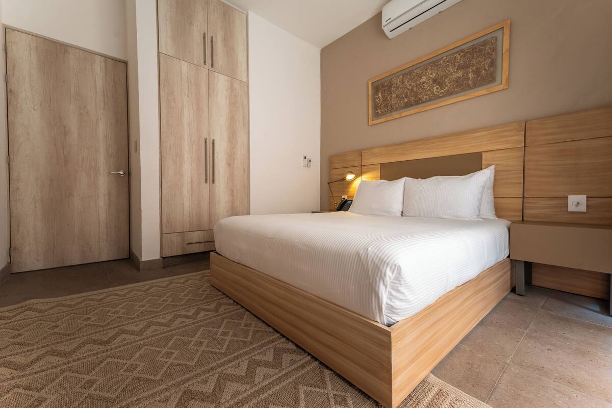 Ein Schlafzimmer mit einem großen Bett, einem Holzschrank und einer Wandklimaanlage.