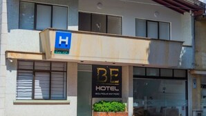 A hotel with a sign indicating a H for handicapped accessibility, a visible entrance, and a small outdoor seating area. - Hotel Boutique Estadio Medellin (Medellín)