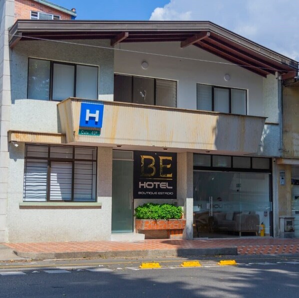 A hotel with a sign indicating a H for handicapped accessibility, a visible entrance, and a small outdoor seating area. - Hotel Boutique Estadio Medellin (Medellín)