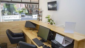 A modern office with a wooden desk, two black office chairs, a computer, a printer, and a window with a view of the street. - Hotel Boutique Estadio Medellin (Medellín)