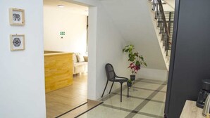 A hotel lobby with a check-in counter, a staircase, and a seating area with a plant. - Hotel Boutique Estadio Medellin (Medellín)