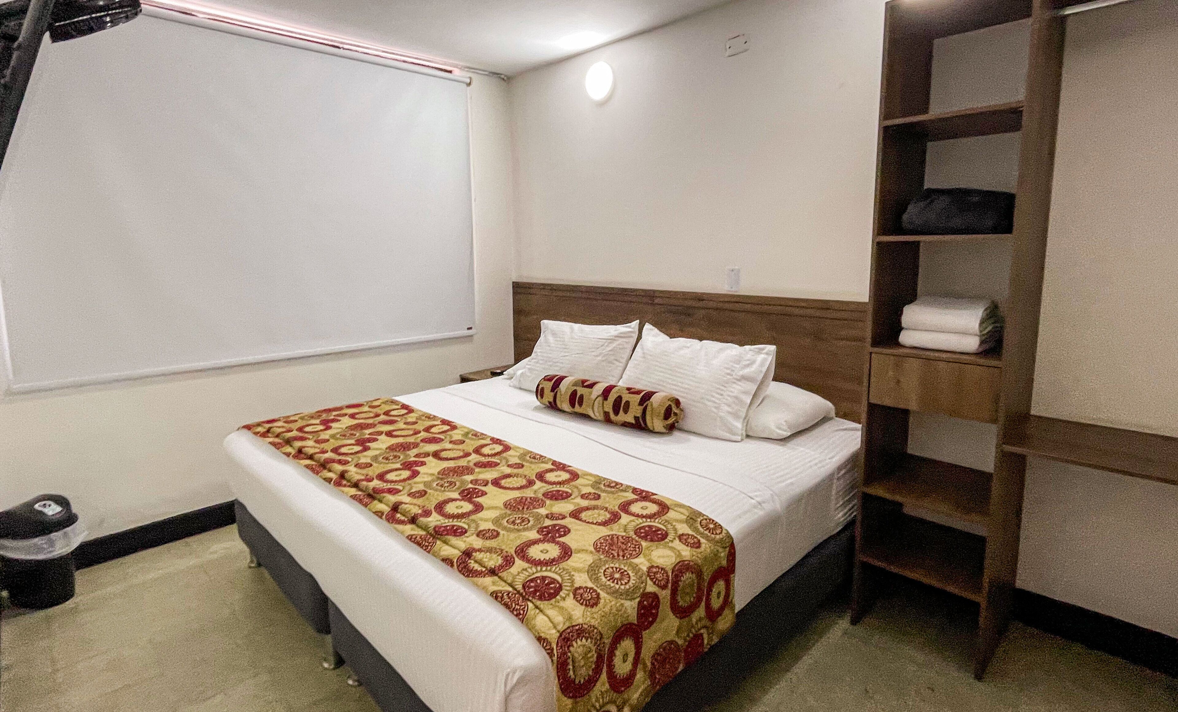 Una camera d'albergo con un letto, una testiera in legno, un armadio e una finestra con persiane.