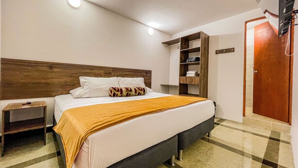 A hotel room with a bed, bedside tables, a wardrobe, and a bathroom door. - Hotel Boutique Estadio Medellin (Medellín)